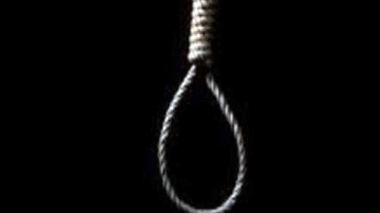 A single noose made of thick rope hangs against a dark black background.