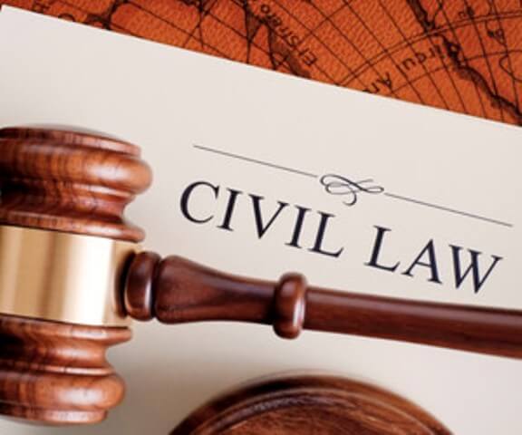 A wooden judge's gavel rests on a document titled "CIVIL LAW" in bold letters, with part of a map visible in the background.