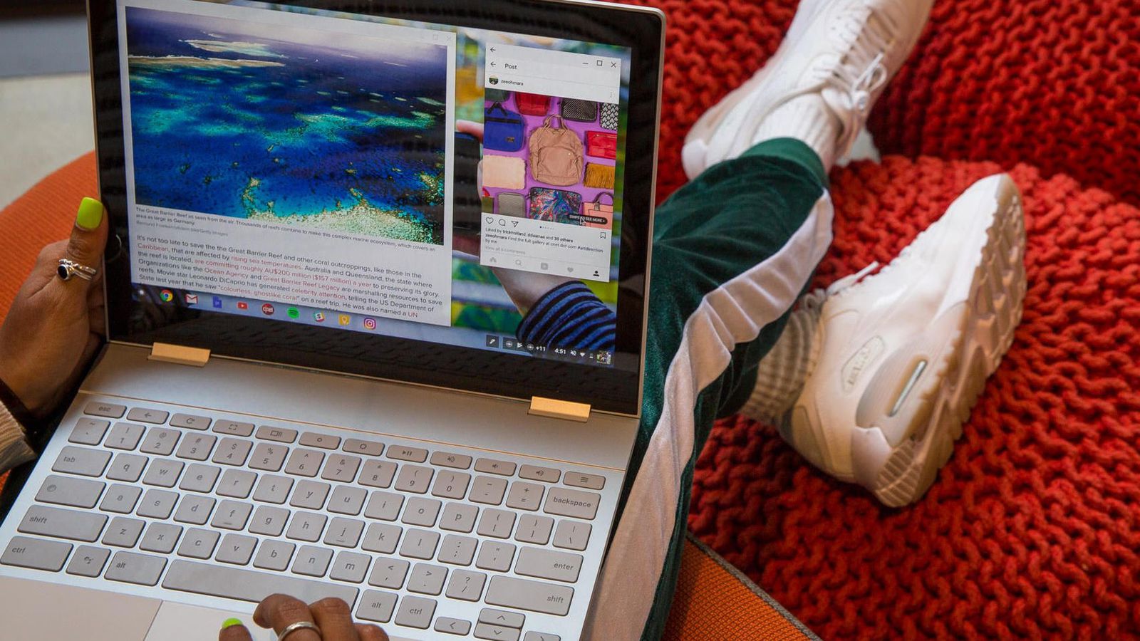 Person with green-painted nails using a white laptop on their lap, viewing colorful images and text on the screen, sitting on a red textured surface, wearing green pants and white sneakers.
