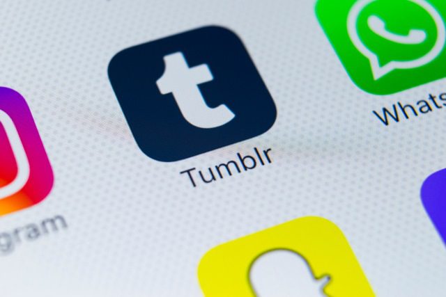 A close-up of a smartphone screen showing app icons, including Tumblr, Snapchat, and WhatsApp, with the Tumblr app icon prominently centered and in focus.