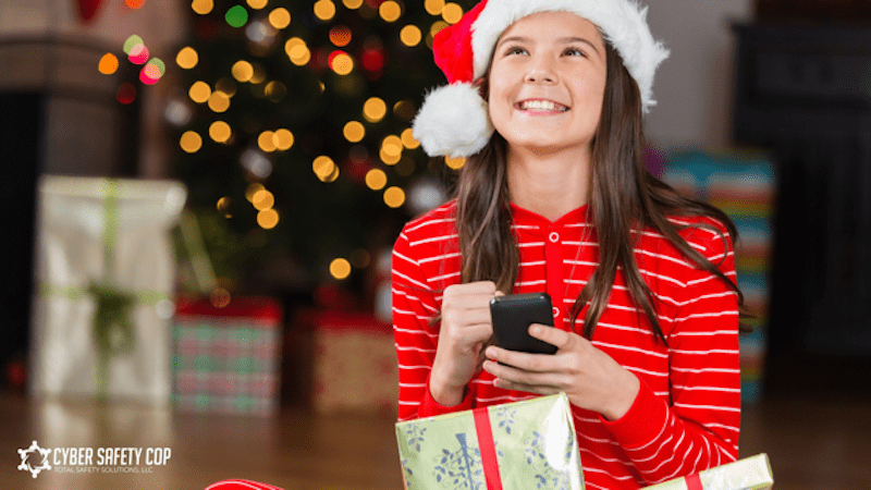A girl in a santa hat holding a phone.