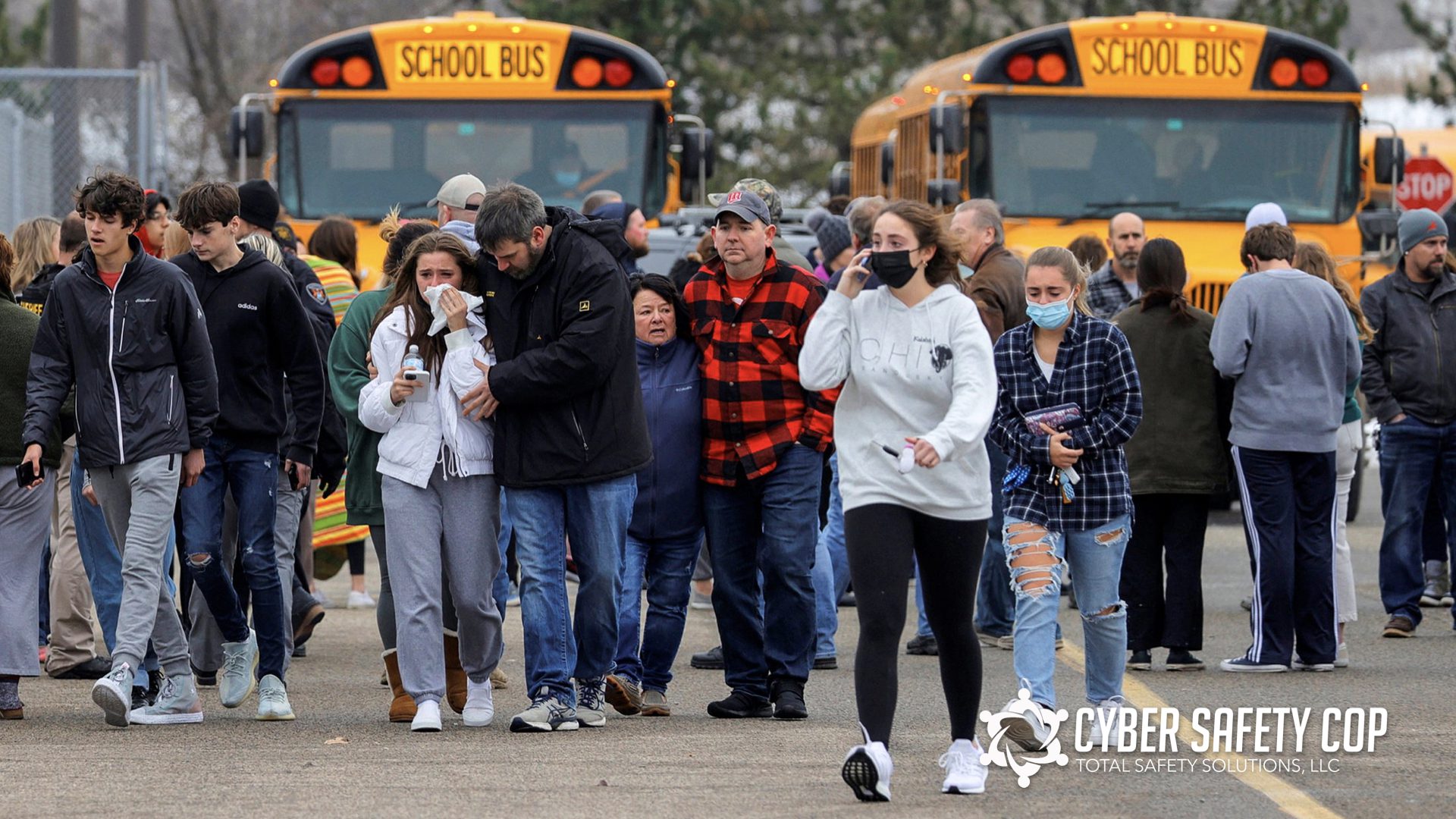 A group of students and adults walk away from two parked school buses, looking concerned. Some are comforting each other, and a few wear face masks. The atmosphere appears tense and serious.