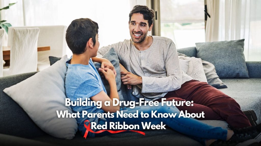 A father and son sit on a couch having a conversation. Text overlay reads, "Building a Drug-Free Future: What Parents Need to Know About Red Ribbon Week," with a red ribbon underlining "Red Ribbon Week"—inspiring parents to support drug-free choices.