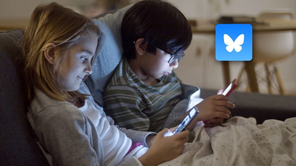 Two children sit close together on a couch, each focused on a tablet or smartphone. The room is dimly lit, highlighting a blue icon with a white butterfly—suggesting Bluesky’s features may help promote cyber internet safety.